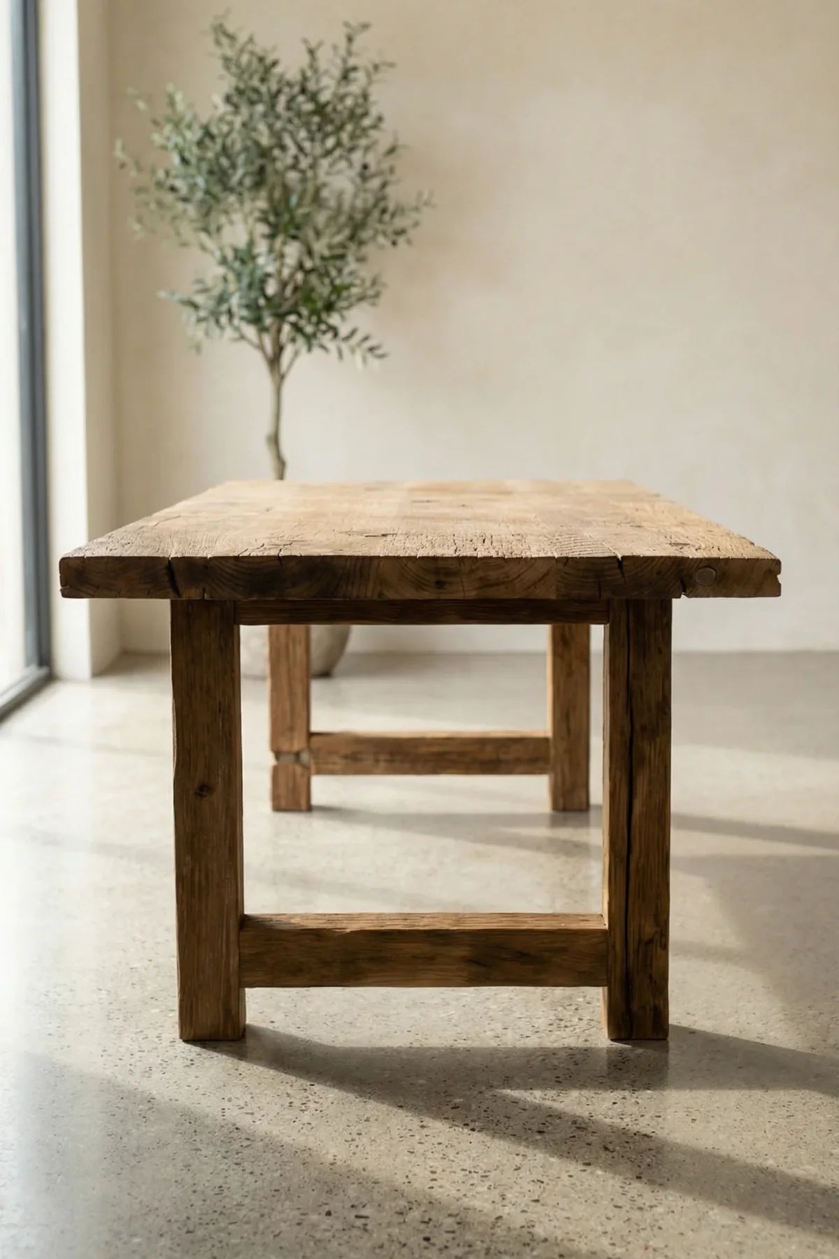 Wooden table in a minimalistic room with a plant in the background
