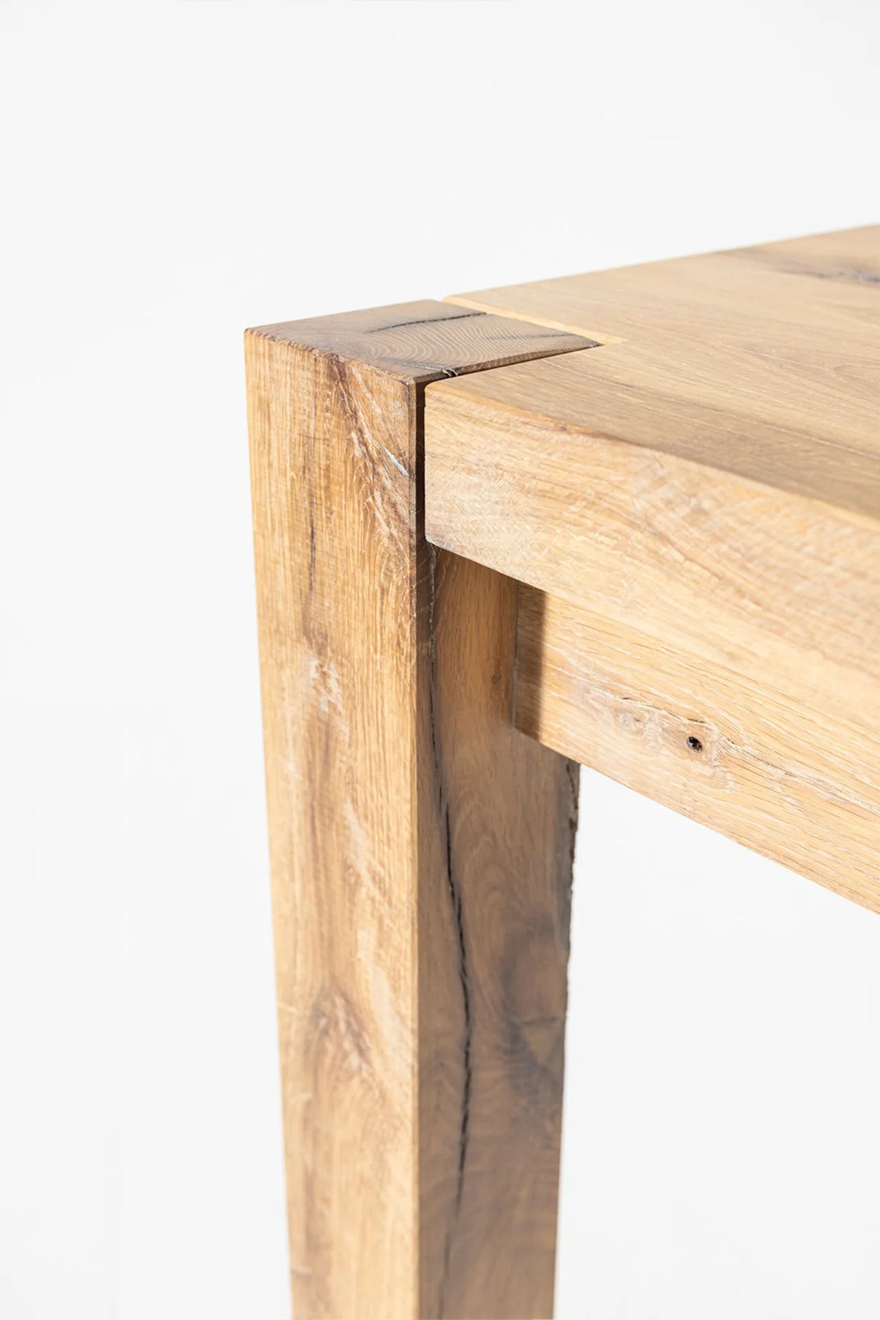 Driftwood reclaimed wood dining table end-grain joinery detail showing block leg locked into the tabletop corner