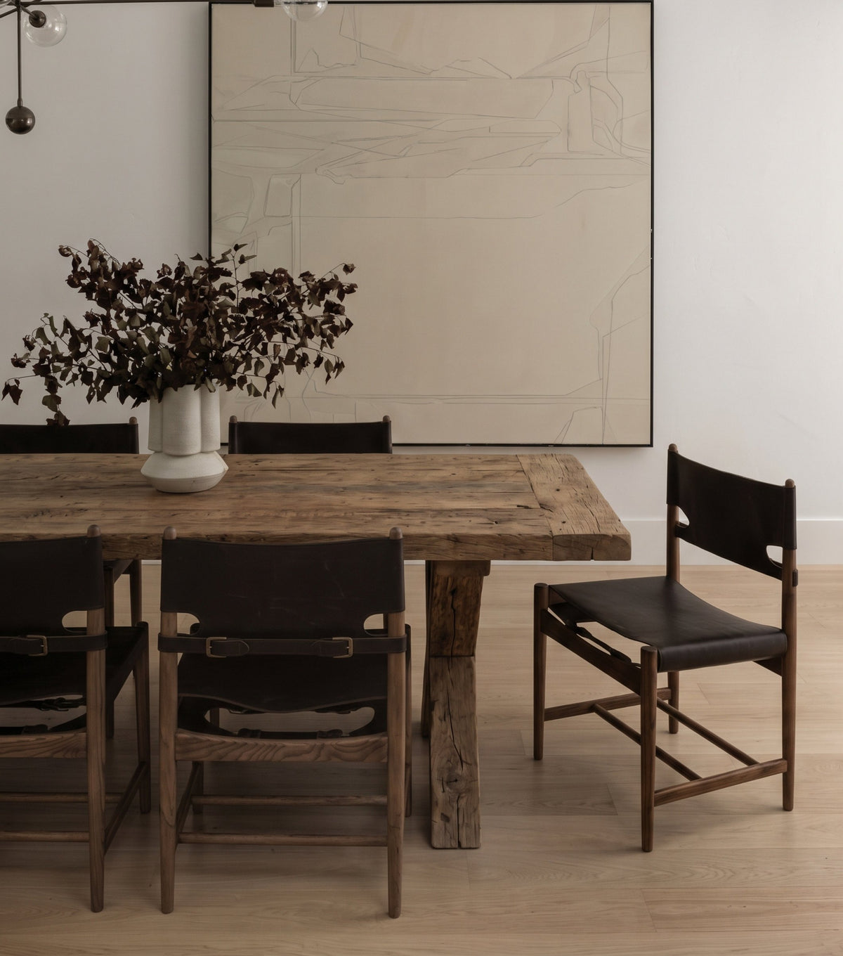 Traverse Reclaimed Oak Dining Table – with black leather chairs beneath a large artwork